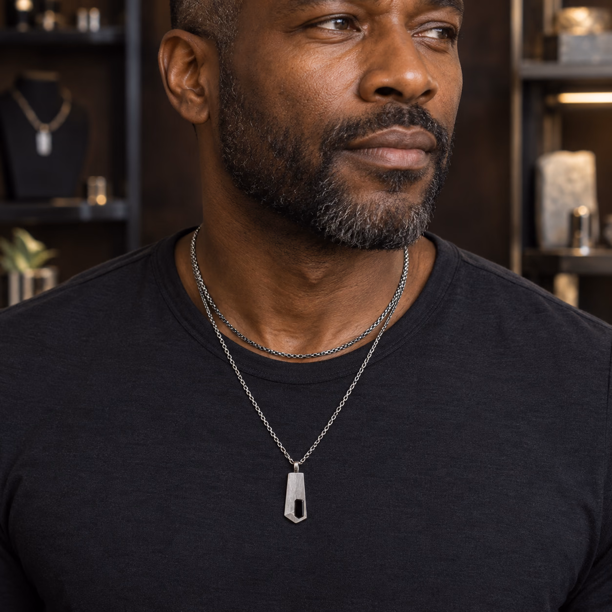 Black man wearing layered oxidized-silver chains and an onyx pendant